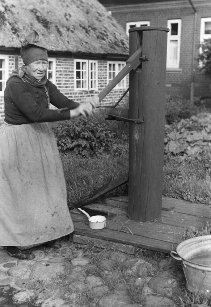 Foto af kvinde ved vandpumpe på en gård ved Fanø i slutningen af 1800-tallet. Billede © Fanø Museum.